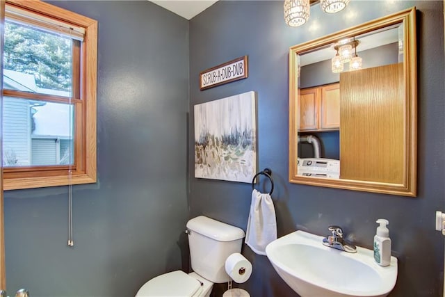 bathroom featuring sink, toilet, and washer / dryer