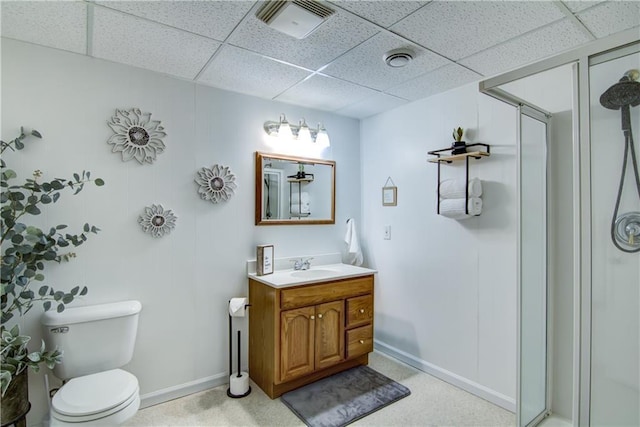 bathroom with toilet, a drop ceiling, walk in shower, and vanity