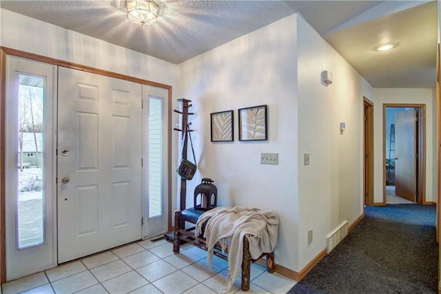 foyer entrance with a textured ceiling and light tile patterned floors