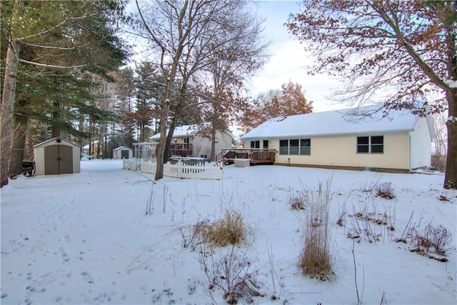 yard covered in snow featuring a wooden deck and a shed