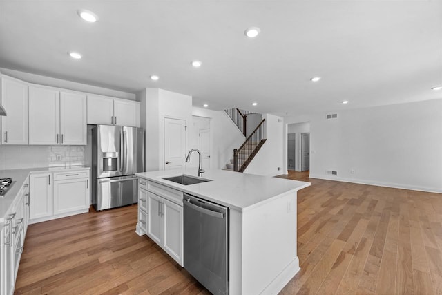 kitchen with sink, a center island with sink, appliances with stainless steel finishes, and white cabinetry