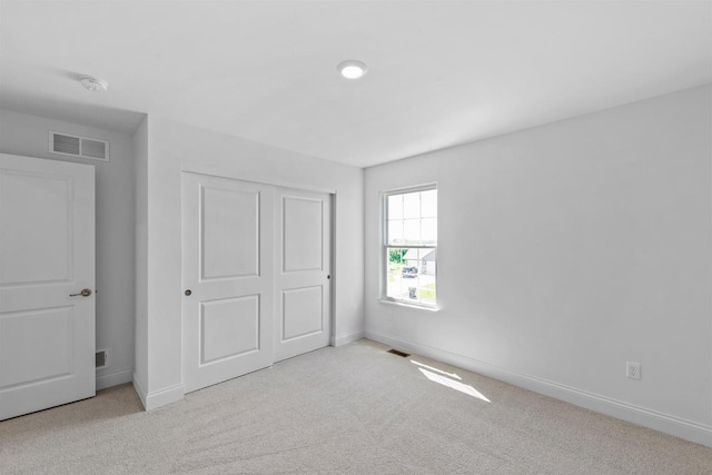 unfurnished bedroom with a closet and light colored carpet