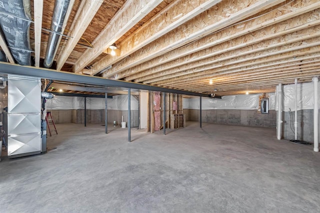 basement featuring electric panel and heating unit