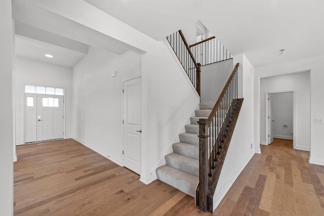 foyer entrance featuring a towering ceiling and light hardwood / wood-style floors