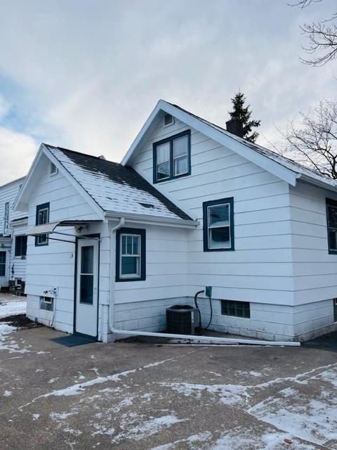 snow covered house with central air condition unit