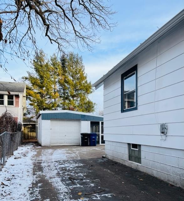 view of snow covered exterior featuring a garage and an outdoor structure