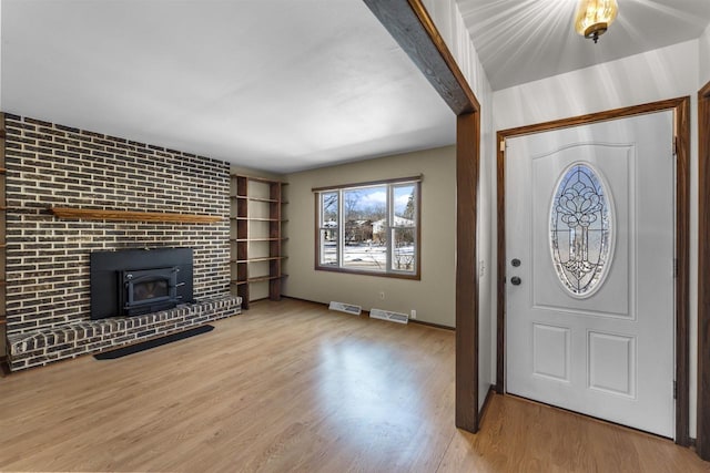 entrance foyer with light hardwood / wood-style floors and a wood stove