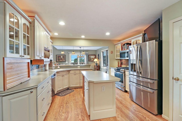 kitchen with kitchen peninsula, a center island, decorative light fixtures, stainless steel appliances, and sink