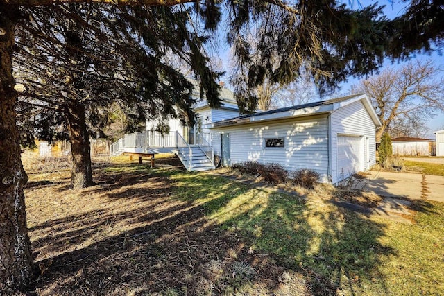 back of property featuring an outbuilding, a lawn, a garage, and a wooden deck