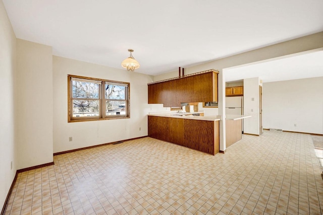 kitchen with kitchen peninsula, white refrigerator, pendant lighting, and an inviting chandelier