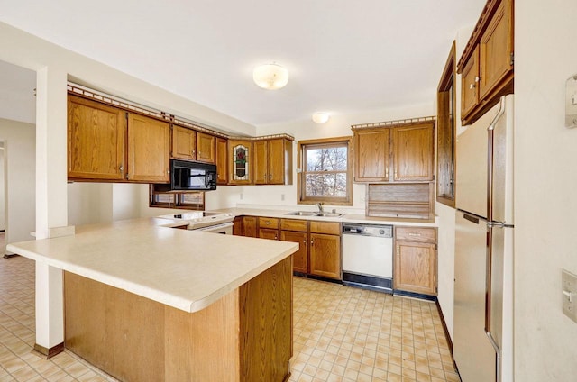 kitchen featuring white appliances, a breakfast bar, sink, and kitchen peninsula