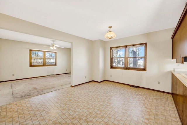 unfurnished dining area featuring light carpet and ceiling fan with notable chandelier