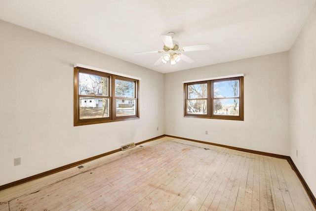 empty room featuring wood-type flooring, ceiling fan, and a wealth of natural light