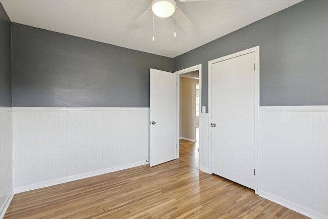 empty room with ceiling fan and light hardwood / wood-style flooring