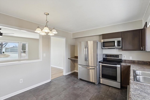 kitchen featuring sink, dark brown cabinets, appliances with stainless steel finishes, pendant lighting, and ceiling fan with notable chandelier