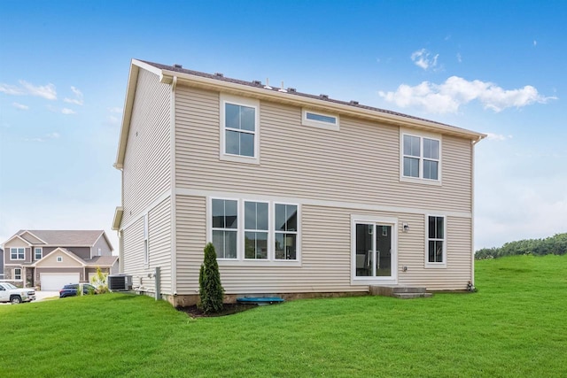 rear view of property featuring a lawn, cooling unit, and a garage