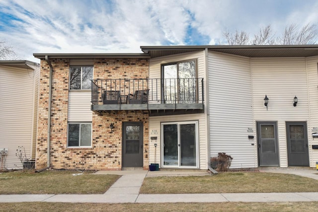 view of property featuring a balcony and a front yard