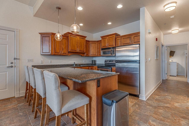 kitchen featuring a breakfast bar area, appliances with stainless steel finishes, pendant lighting, a kitchen island, and sink