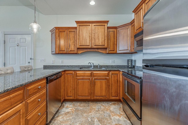 kitchen featuring dark stone countertops, stainless steel appliances, kitchen peninsula, sink, and decorative light fixtures