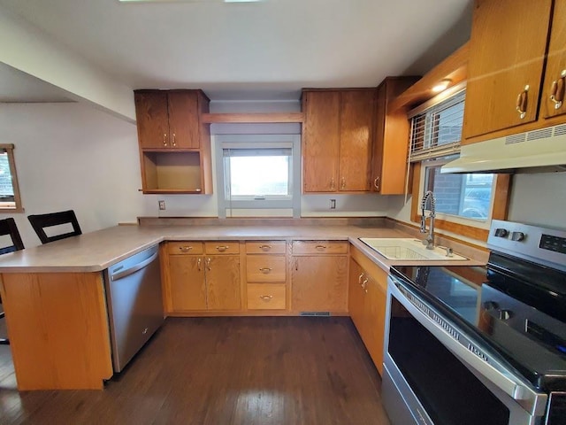 kitchen with stainless steel appliances, sink, a kitchen bar, kitchen peninsula, and dark hardwood / wood-style flooring