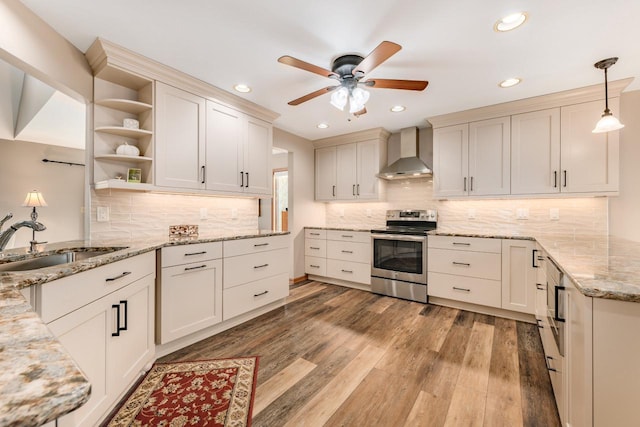 kitchen with decorative light fixtures, stainless steel electric range oven, wall chimney range hood, and light stone counters