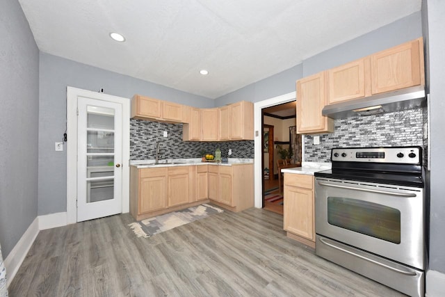 kitchen with light brown cabinetry, electric range, exhaust hood, and sink