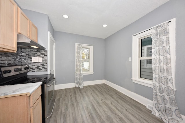 kitchen featuring light wood-type flooring, stainless steel electric stove, tasteful backsplash, and light brown cabinets