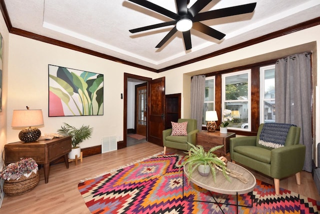 living room with a raised ceiling, ceiling fan, light hardwood / wood-style flooring, and a textured ceiling