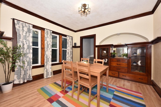 dining room featuring a textured ceiling, light hardwood / wood-style flooring, and ornamental molding