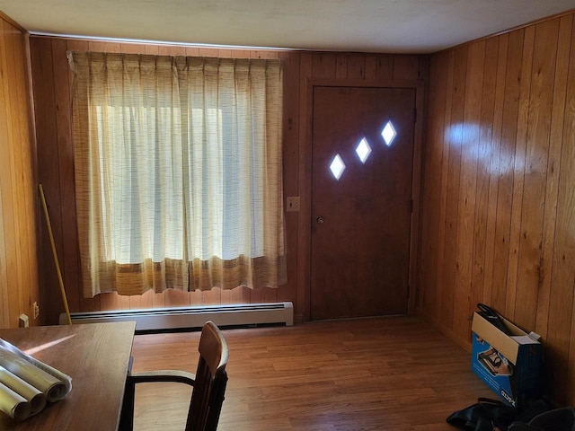 entryway featuring baseboard heating, wooden walls, and a healthy amount of sunlight