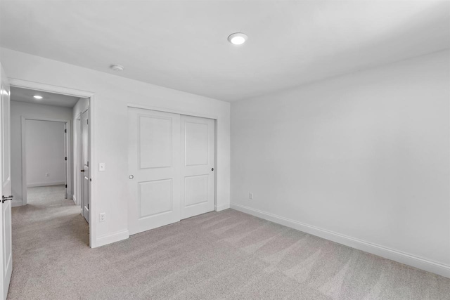 unfurnished bedroom with a closet and light colored carpet