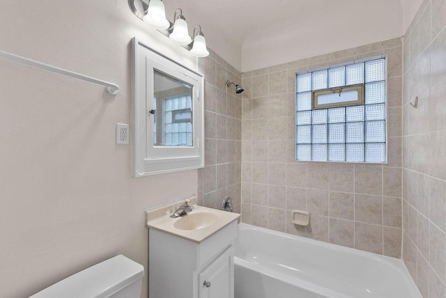 full bathroom featuring toilet, vanity, a healthy amount of sunlight, and tiled shower / bath