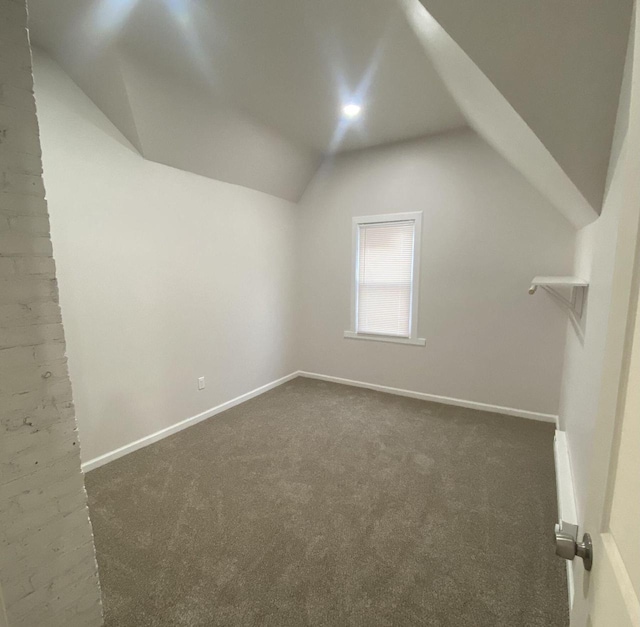 additional living space featuring lofted ceiling and dark carpet