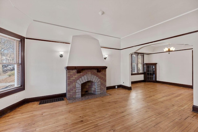 unfurnished living room featuring light hardwood / wood-style floors, a notable chandelier, and a fireplace