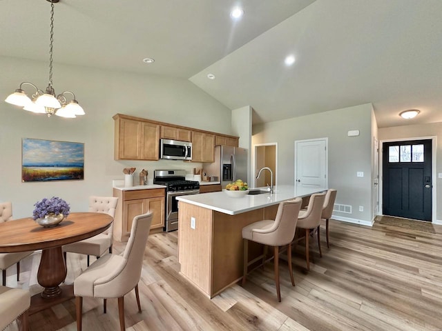 kitchen with sink, a center island with sink, a chandelier, pendant lighting, and appliances with stainless steel finishes