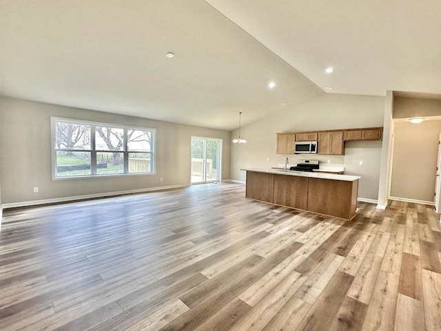 kitchen featuring a center island with sink, hanging light fixtures, light wood-type flooring, a notable chandelier, and stove