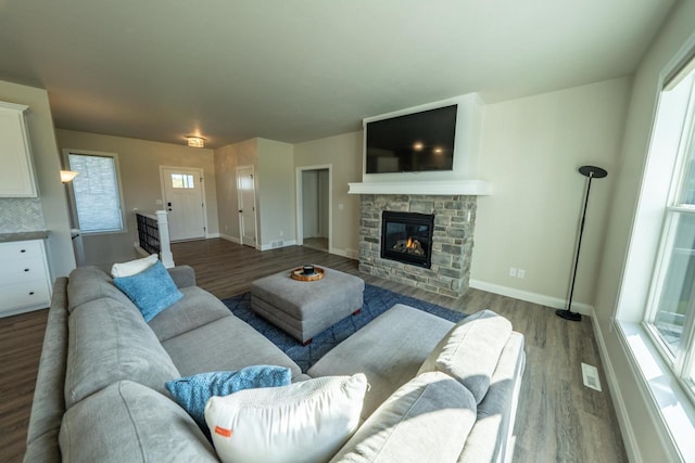 living room featuring a stone fireplace, a wealth of natural light, and hardwood / wood-style flooring