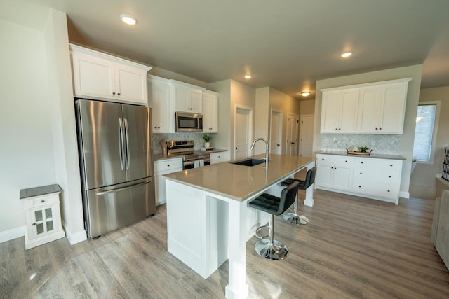 kitchen featuring white cabinets, a center island with sink, appliances with stainless steel finishes, and sink