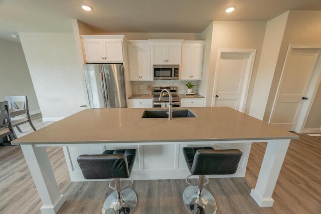 kitchen with a breakfast bar, stainless steel appliances, white cabinetry, and a spacious island