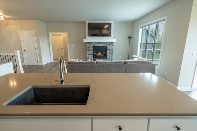 kitchen with sink, a fireplace, hardwood / wood-style floors, and white cabinetry