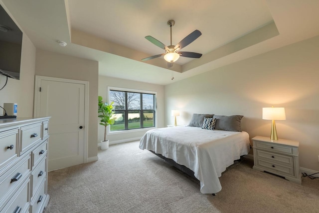 carpeted bedroom with ceiling fan and a tray ceiling