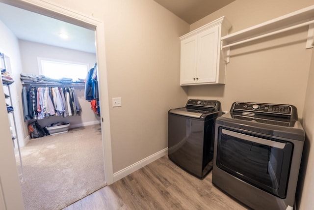 washroom featuring light hardwood / wood-style floors, cabinets, and washing machine and clothes dryer