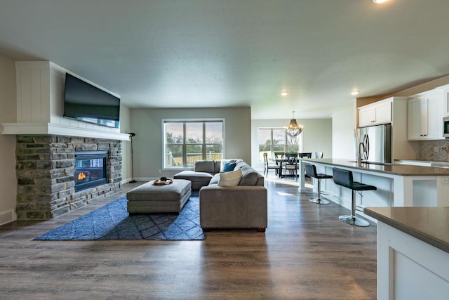 living room with a fireplace, dark wood-type flooring, and sink