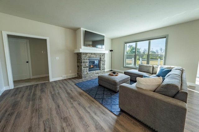 living room with hardwood / wood-style flooring and a stone fireplace