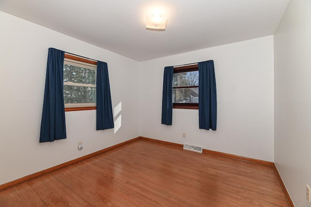 spare room featuring a wealth of natural light and hardwood / wood-style floors