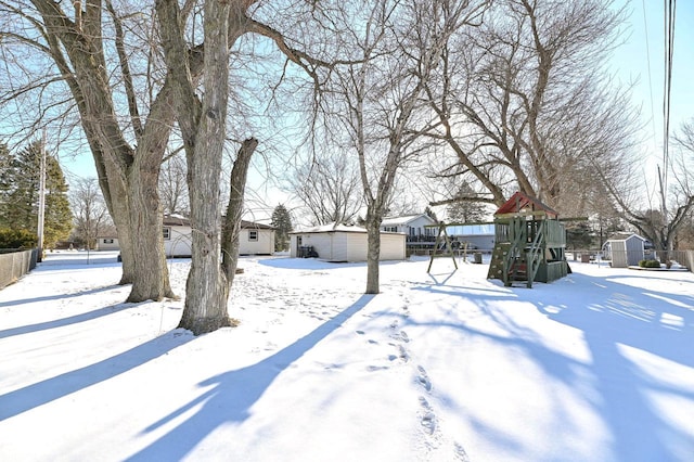 snowy yard featuring a playground and a shed