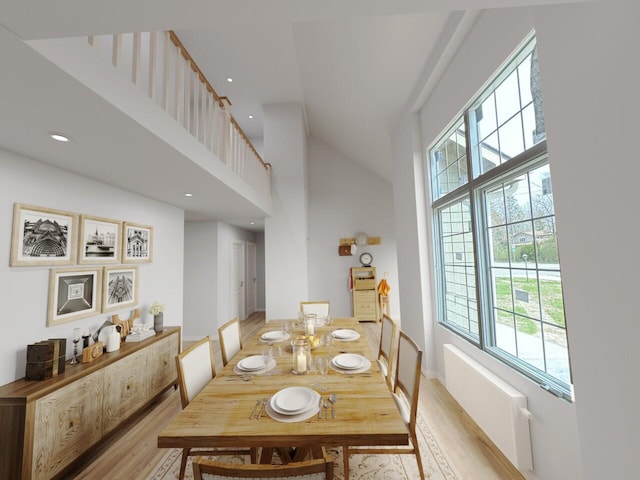 dining area with a high ceiling, plenty of natural light, radiator heating unit, and light hardwood / wood-style floors