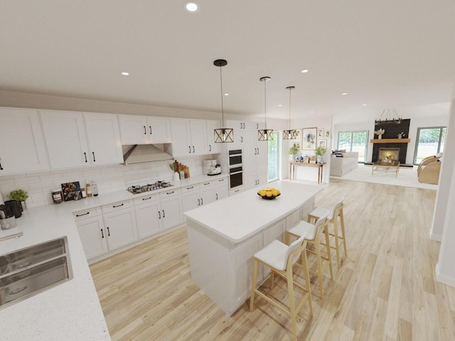 kitchen with white cabinetry, backsplash, stainless steel gas cooktop, light hardwood / wood-style flooring, and a breakfast bar area