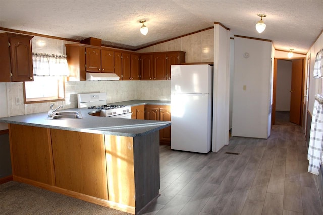 kitchen featuring white appliances, kitchen peninsula, a textured ceiling, lofted ceiling, and sink