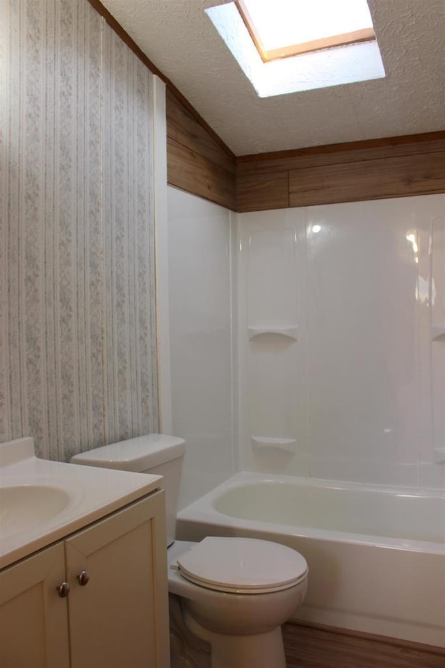 full bathroom with toilet, vaulted ceiling with skylight, shower / washtub combination, wood-type flooring, and vanity